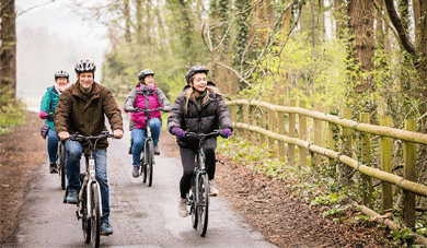 4 people on electric bikes riding through the countryside